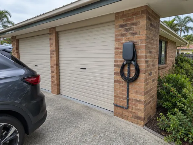 Wall-mounted EV charger on a brick garage pillar beside a driveway in Parkwood